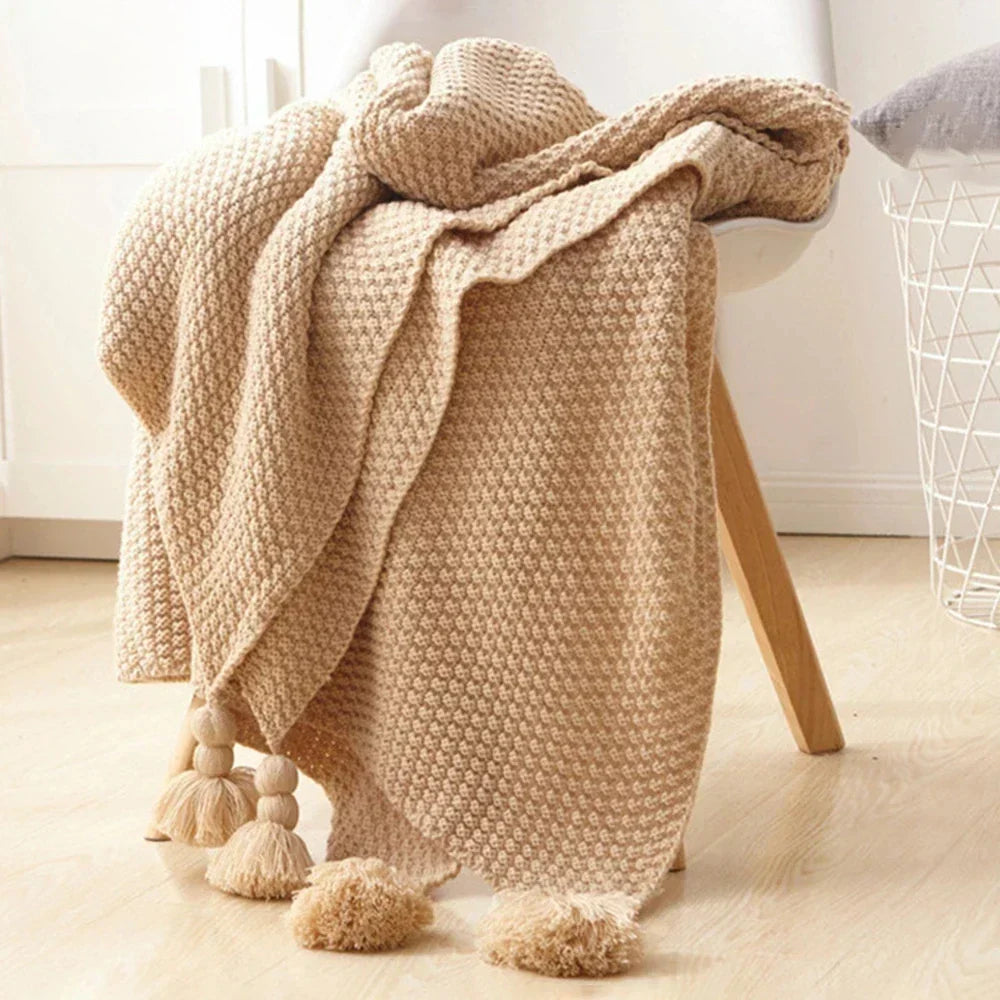 Close-up of knitted wool blanket texture & decorative tassels, highlighting natural fibers.