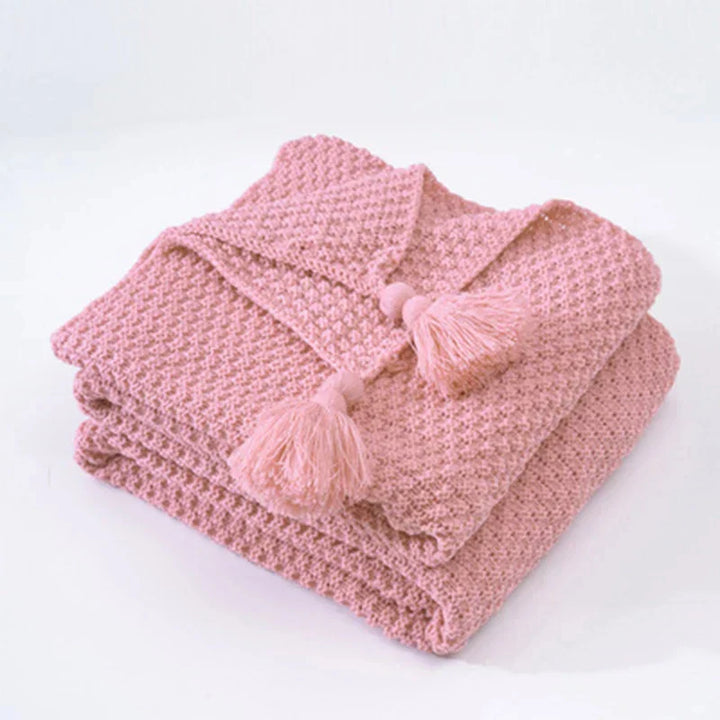 Cozy knitted wool bed blanket with tassels, perfect for a warm night's sleep.