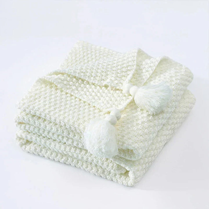 Soft, chunky knit wool blanket with elegant tassels, ideal for cozy evenings.