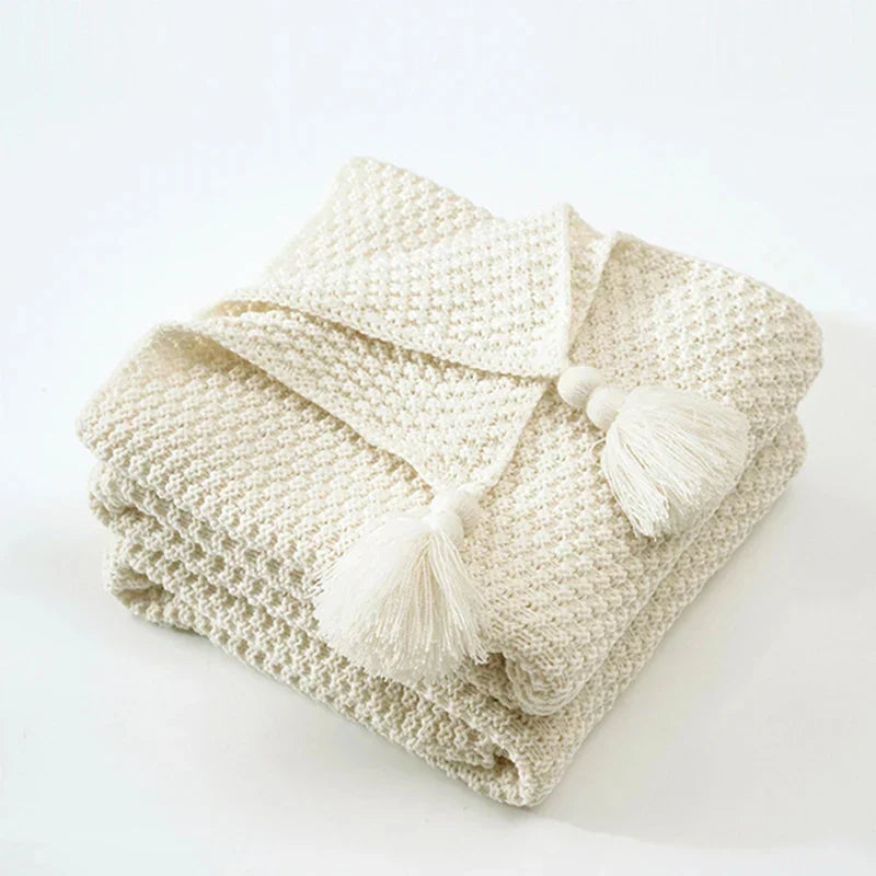 Warm knitted wool blanket with braided tassels, modern Scandinavian home decor.