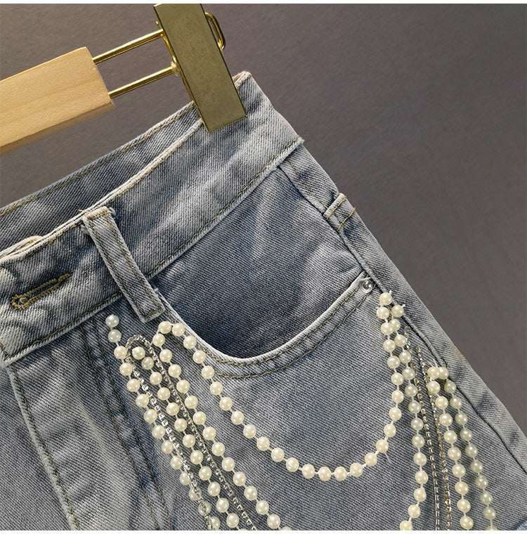 Versatile light blue denim shorts for women, featuring unique pearl embellishments and chic tassel fringe.