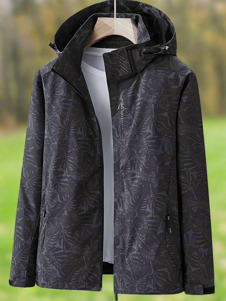 Hooded women's waterproof jacket, ideal for summer, with a modern leaf print design.