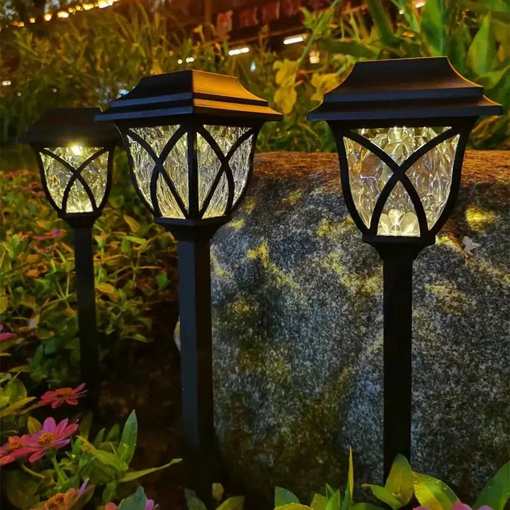 Set of LunaGlow solar LED path lights lining a stone walkway, providing bright outdoor lighting for safety.