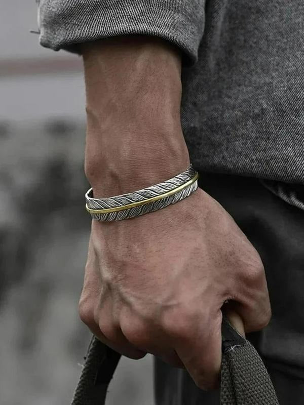 Close-up of a men's stainless steel feather cuff bracelet, showcasing intricate feather detailing and polished finish.