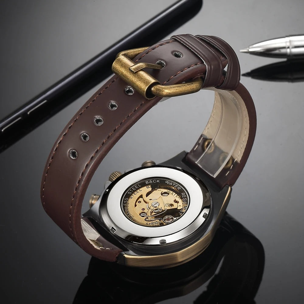 Men's hand-wound mechanical skeleton timepiece on wrist, antique gold case, exposed movement, rich leather strap.