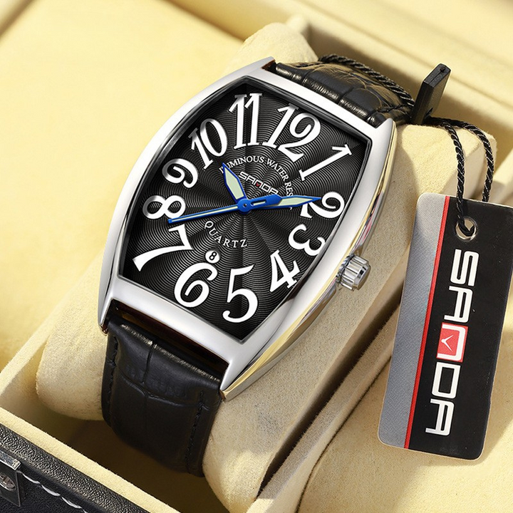 Close-up of men's Art Deco tonneau watch, polished case, textured leather strap.