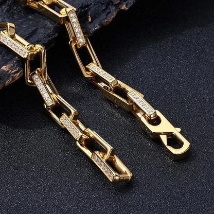 Stylish men's hand wearing a dazzling gold chainlink bracelet with sparkling zirconia, statement jewelry.