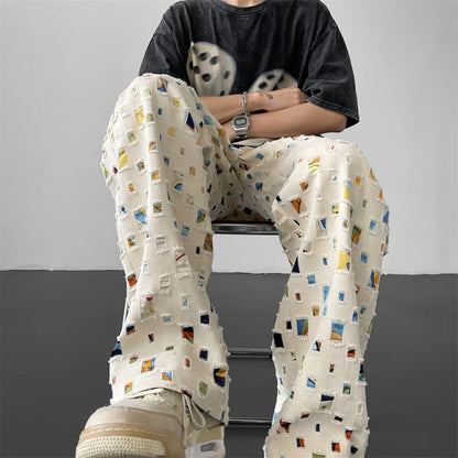 Full shot of men's distressed pants with edgy rips and intricate patchwork, perfect for urban style.