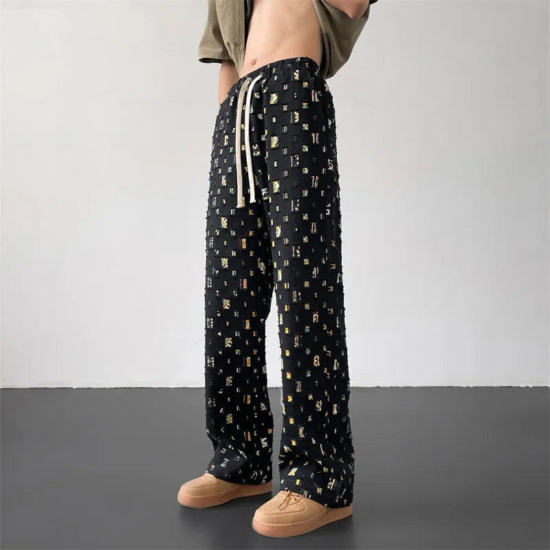 Bold men's fashion pants with distressed rips and custom patchwork, ideal for an edgy urban look.