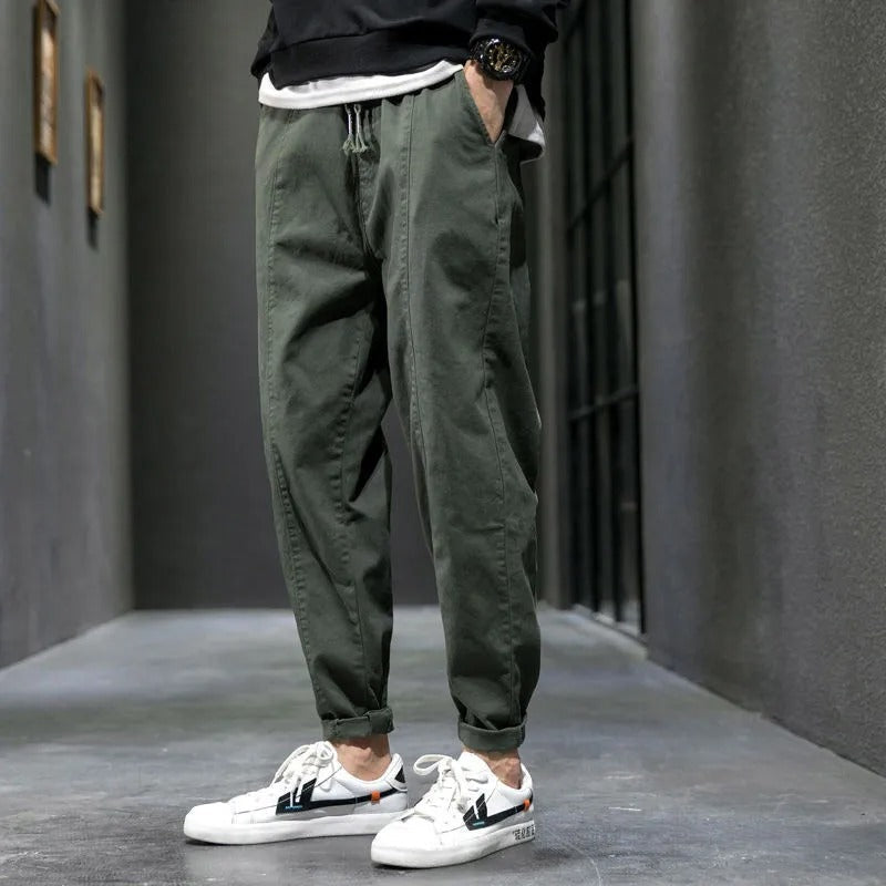 Man sitting in navy tapered joggers, showcasing flexible comfort for athleisure, loungewear & casual activities.