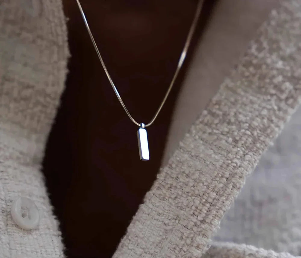 Close-up of a men's gold bar pendant necklace, showcasing its sleek, minimalist stainless steel design.