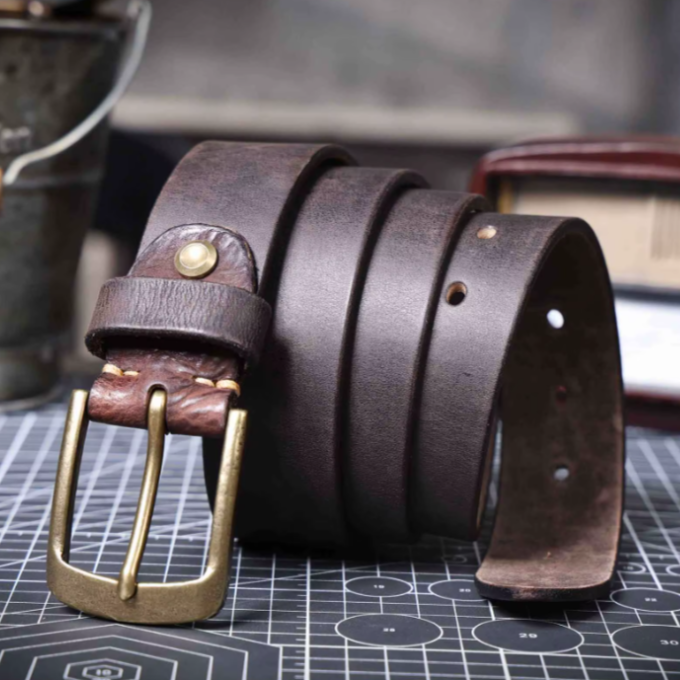 Stack of durable men's cowhide leather belts in varying brown shades. Classic waist accessories.