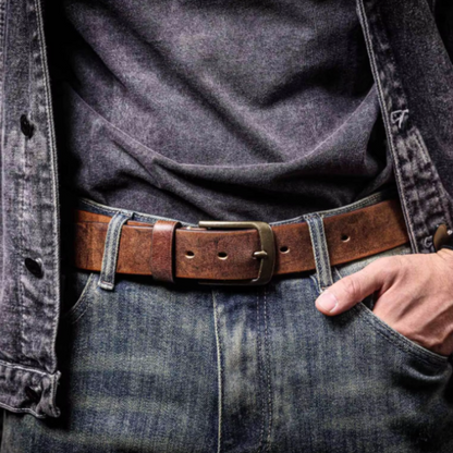 Men's brown cowhide leather belt with silver buckle worn on blue jeans. Classic, durable accessory.