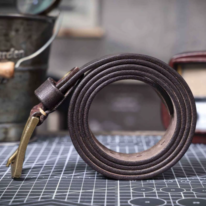 Angled view of a men's classic brown cowhide leather belt. Durable waist accessory with vintage style.