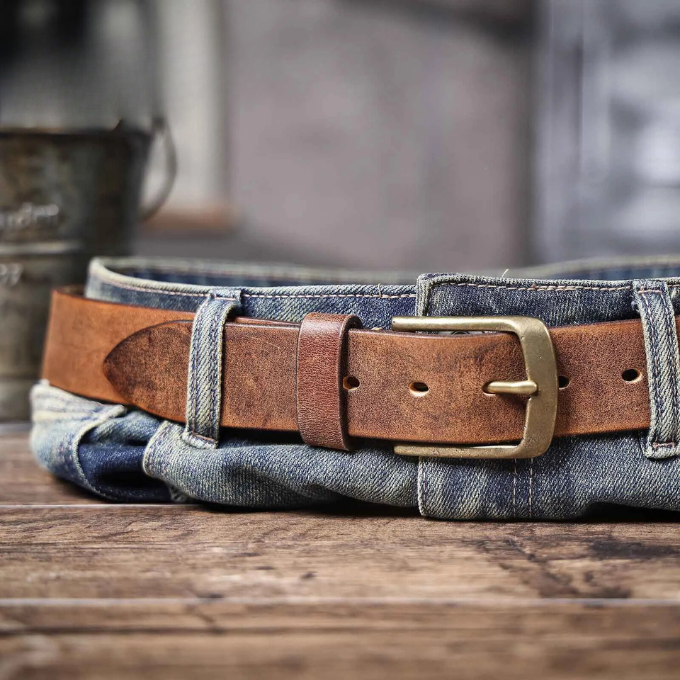 Close-up of a silver buckle on a classic men's durable brown cowhide leather belt. Vintage style.