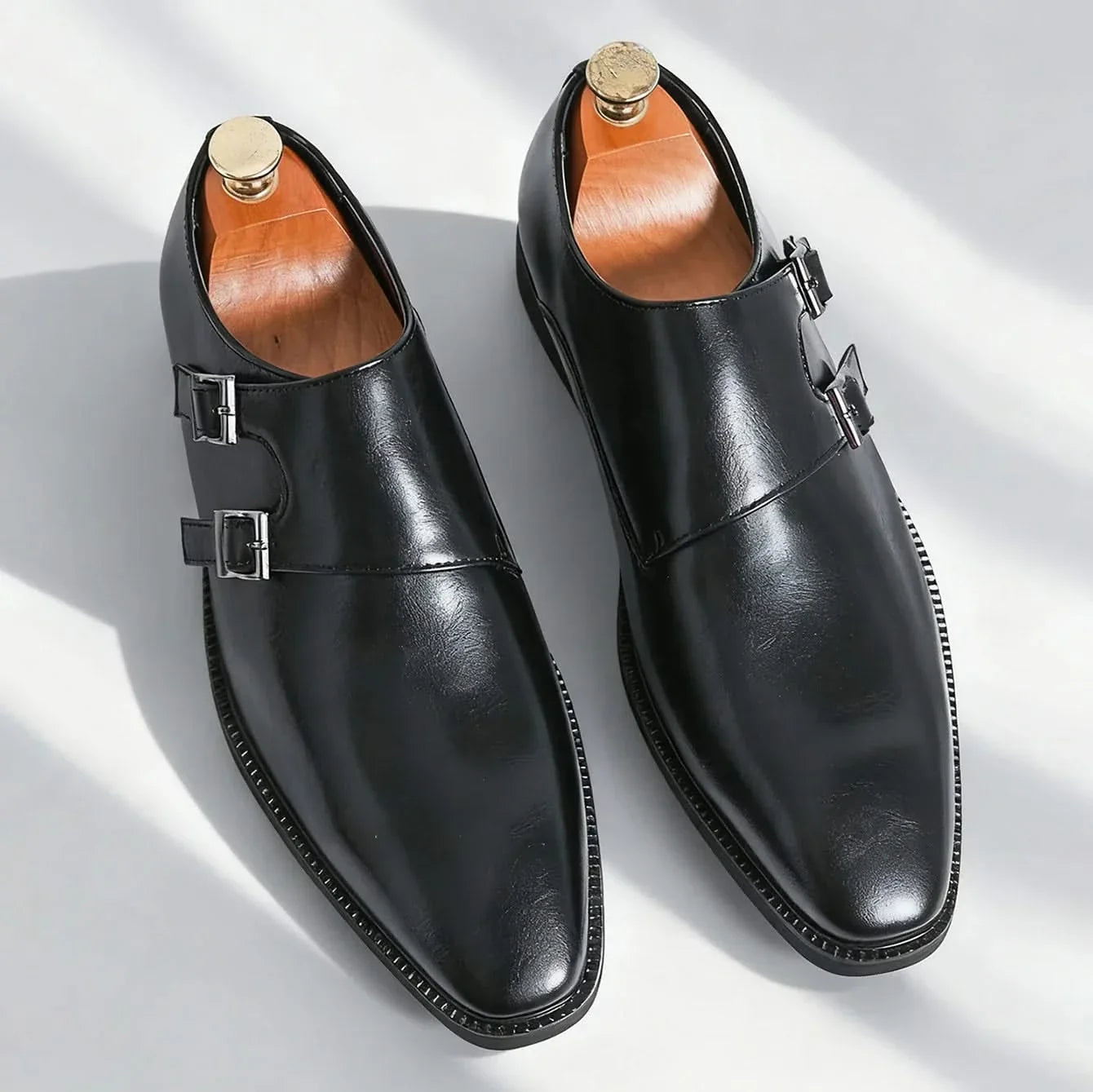 Close-up of the shining double buckle on men's black leather Regent Monk Loafers, a detail of elegant design.