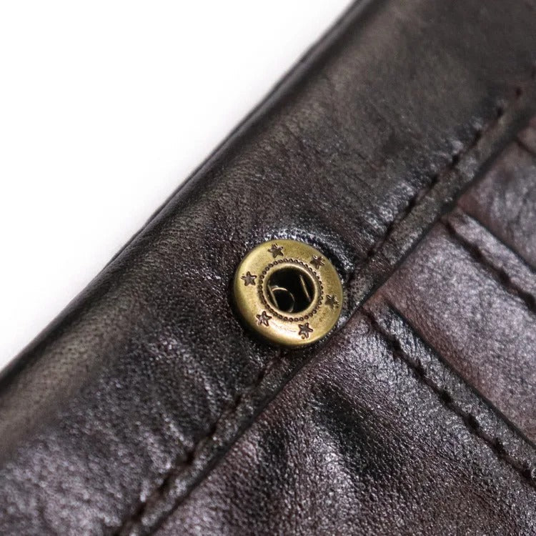 Close-up of durable stitching on a men's vintage leather bifold wallet with snap closure. Rugged style.