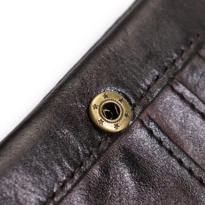 Close-up of durable stitching on a men's vintage leather bifold wallet with snap closure. Rugged style.