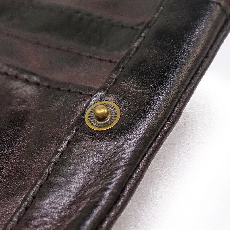 Men's vintage leather bifold wallet, slim & rugged, held in hand, showing compact size & quality.