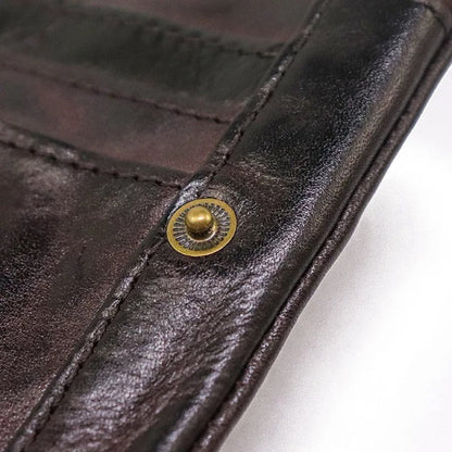 Men's vintage leather bifold wallet, slim & rugged, held in hand, showing compact size & quality.