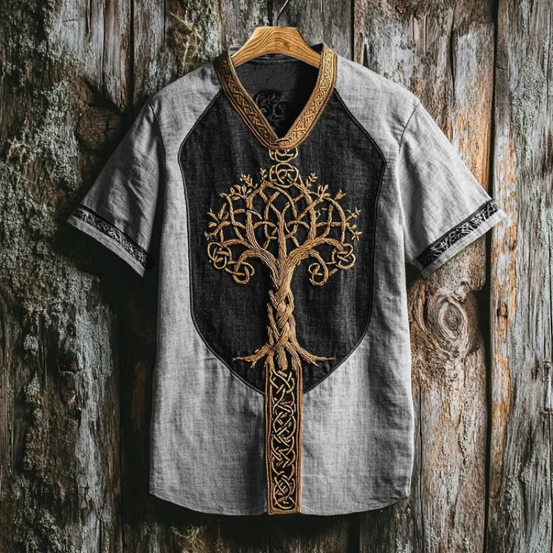 Close-up of men's short sleeve shirt, detailed Yggdrasil embroidery, Celtic-inspired mythic fashion.