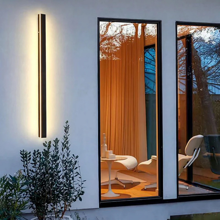 Multiple LineaGlow modern outdoor LED wall lamps creating uniform landscape lighting.