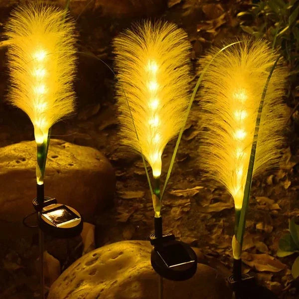 A single reed solar light standing tall in a flower bed, serving as elegant garden landscape lighting.