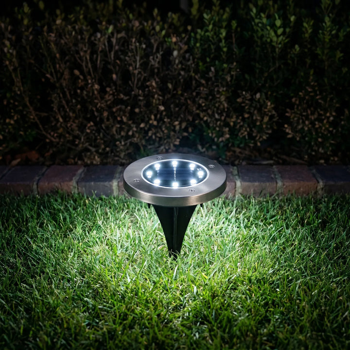 Warm glow from waterproof solar disk lights enhancing outdoor garden and landscape ambiance at night.