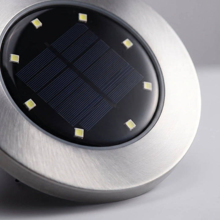 Array of outdoor solar pathway disk lights providing efficient, eco-friendly landscape and garden lighting.