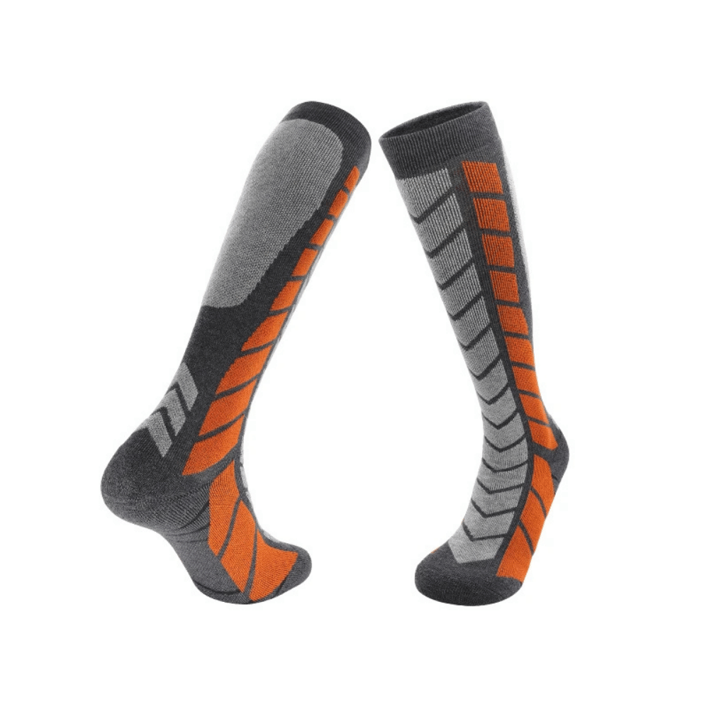Ski accessories collection: black thermal socks, goggles, and gloves on a snow background