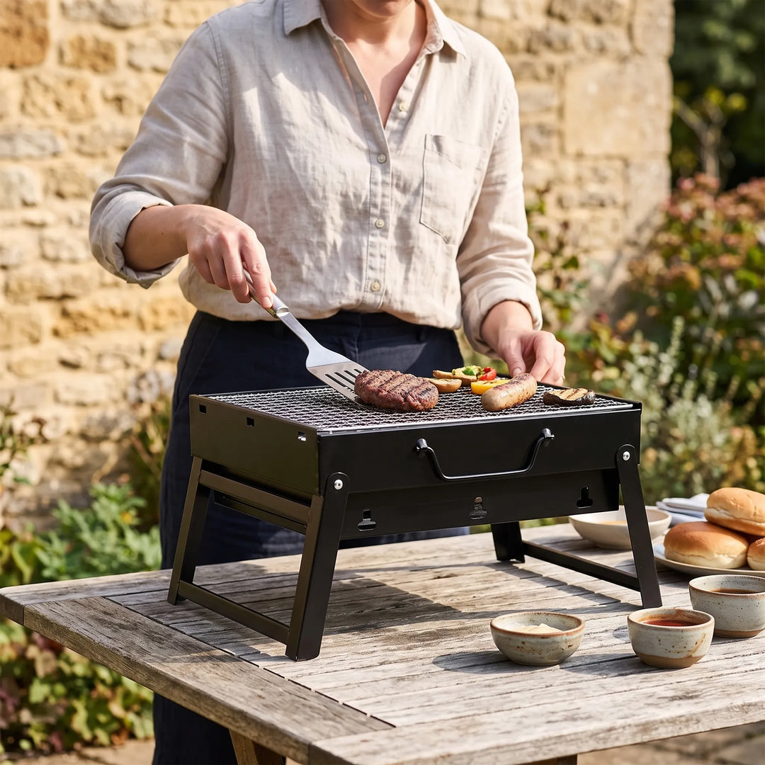 Portable folding charcoal grill for easy outdoor cooking, camping, and picnics.