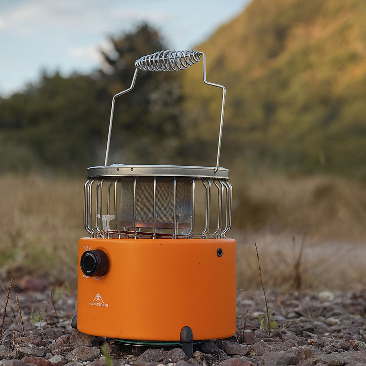 Portable outdoor camping heater and cooker in a natural setting, ready for use