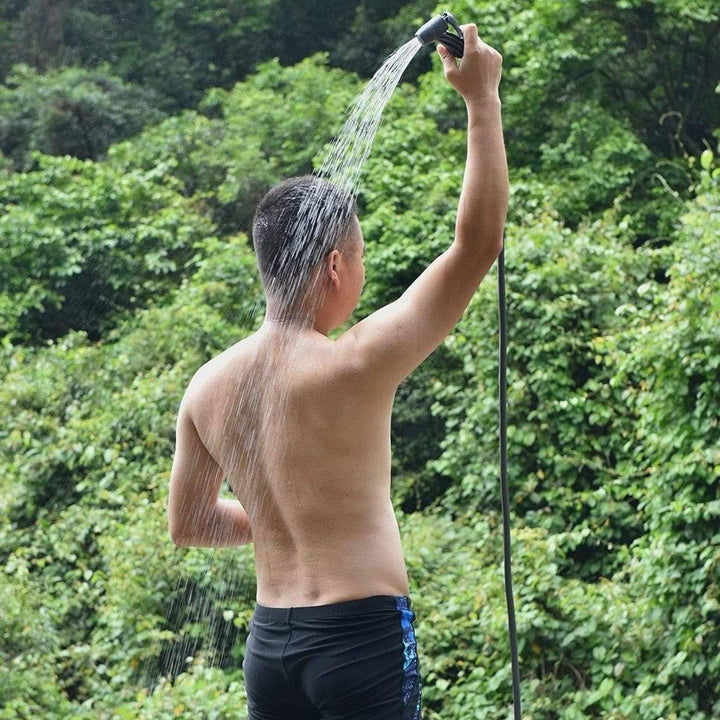 Blue portable pressure shower water bag, 11L, hanging from a tree for outdoor camping hygiene