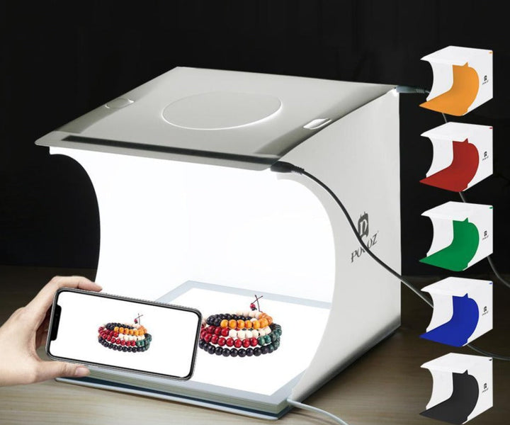 Content creator using a portable LED photo studio lightbox for crisp, high-quality product photography.