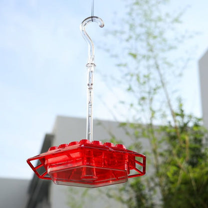 Transparent hummingbird feeder, showcasing nectar, with ant moat, ready for backyard wildlife.