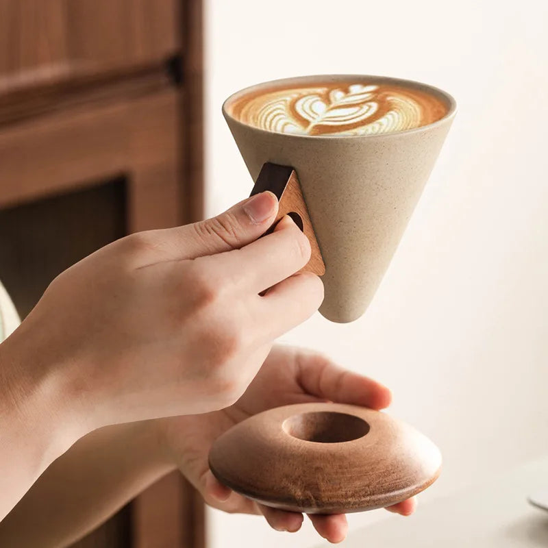 Sculptural ceramic cone mug set with modern design, perfect for coffee or tea. Includes wood base.