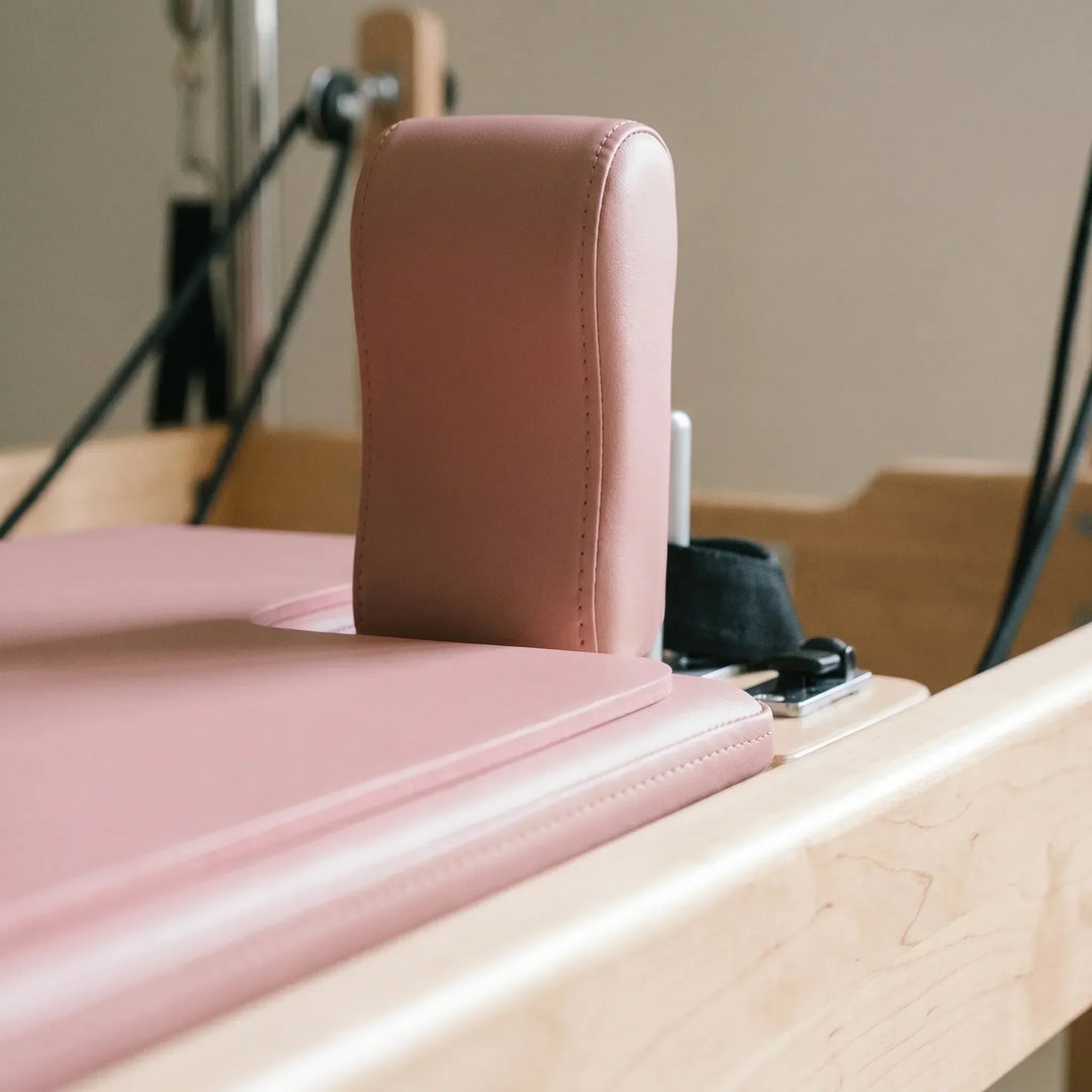 Unisex shaped Pilates pad for reformers, providing soft support & grip in studio. Essential workout accessory.