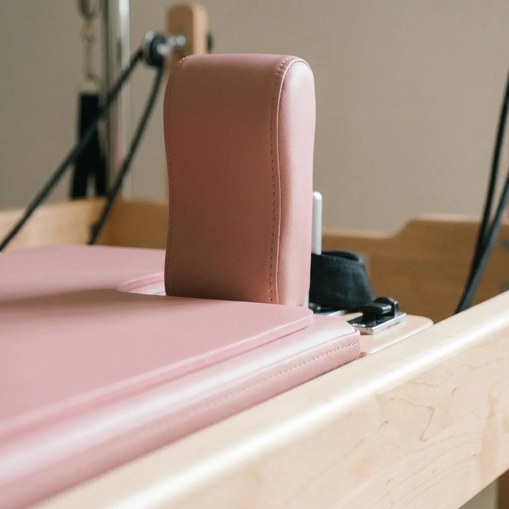 Unisex shaped Pilates pad for reformers, providing soft support & grip in studio. Essential workout accessory.