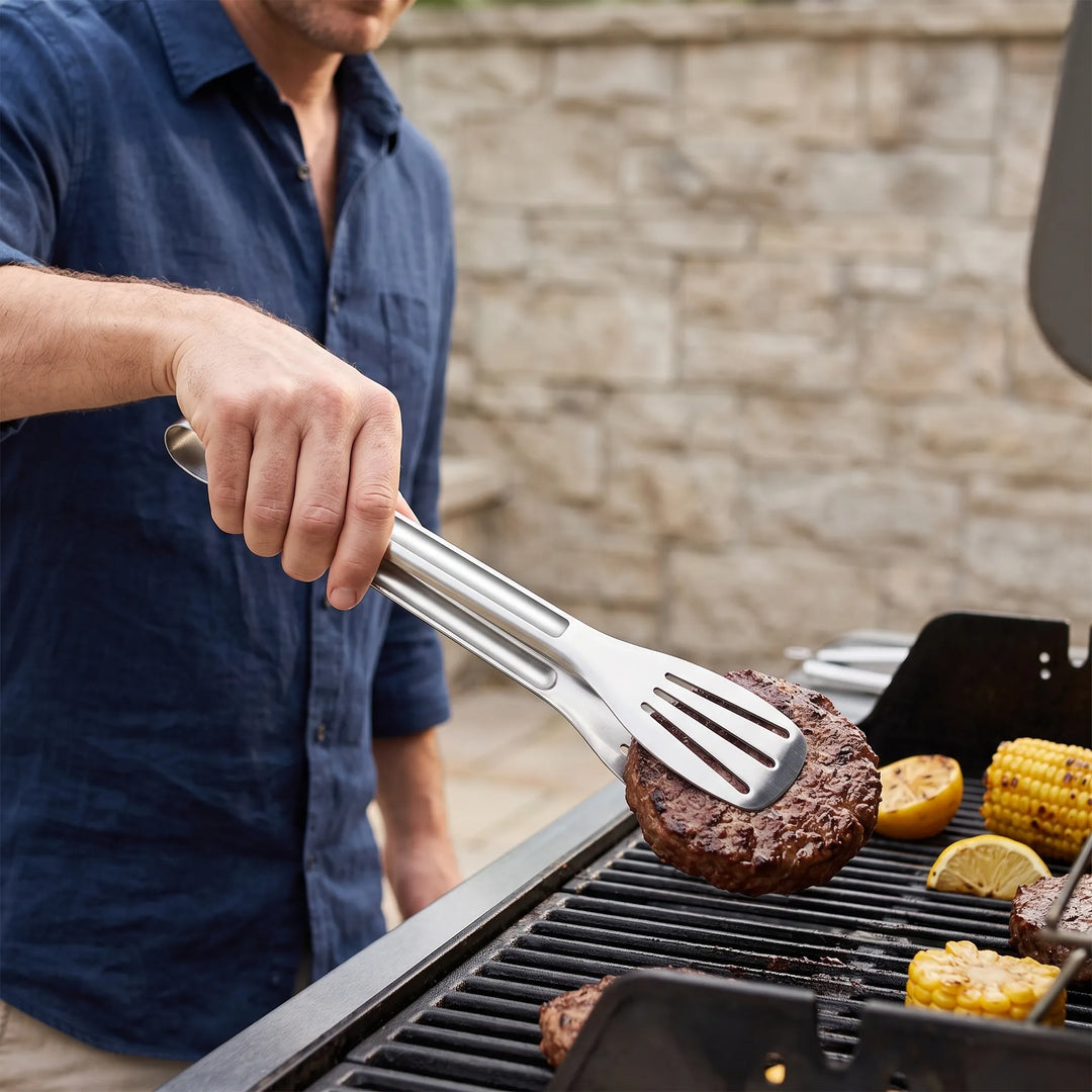Slotted stainless steel kitchen tongs for versatile cooking, grilling, and serving food.