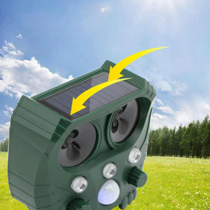 Outdoor solar ultrasonic animal repellent installed in a vibrant garden setting.