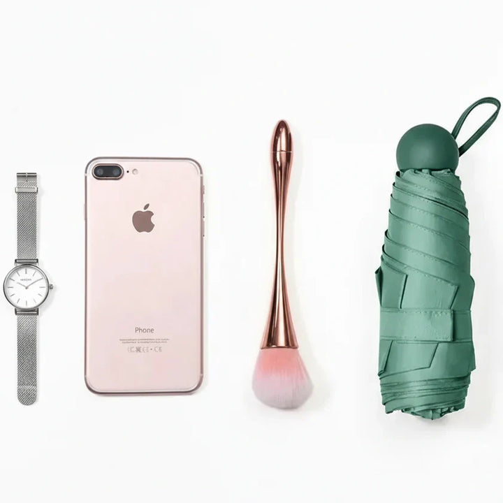 Compact pink travel umbrella with capsule design, offering portable weather protection.