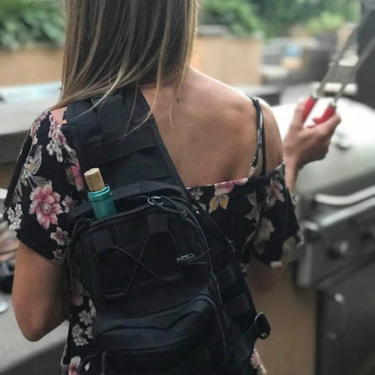 Man wearing a black tactical sling backpack outdoors, demonstrating its comfortable fit as a chest pack.