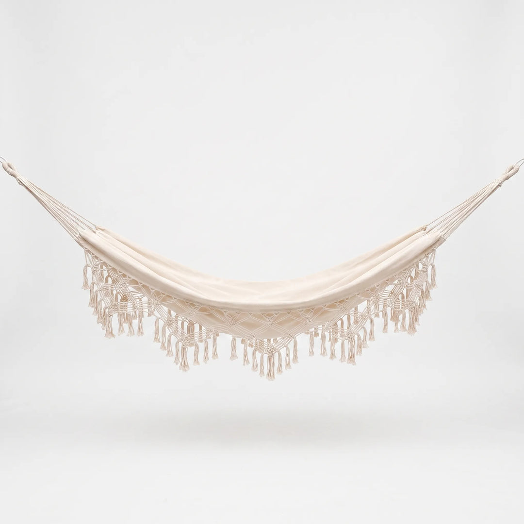 Versatile tasseled hammock chair or bed for outdoor patios; stylish bohemian hanging furniture for gardens.
