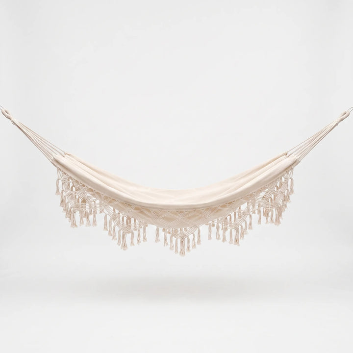 Versatile tasseled hammock chair or bed for outdoor patios; stylish bohemian hanging furniture for gardens.