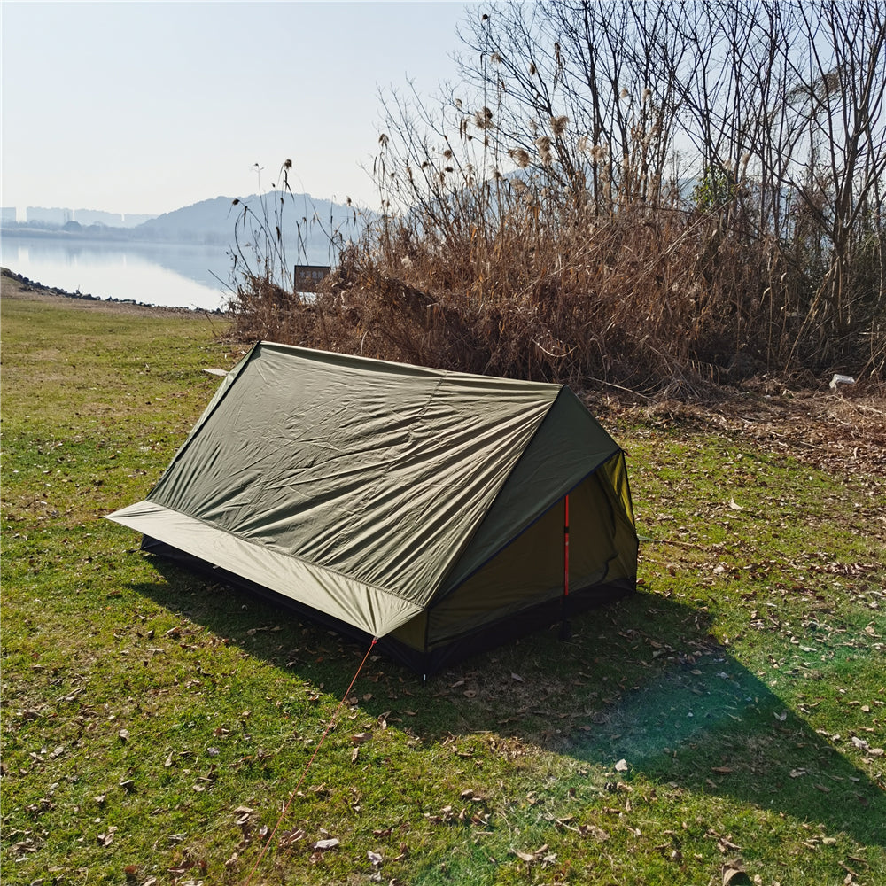 A-frame camping shelter with a scenic lake and mountains in the background.