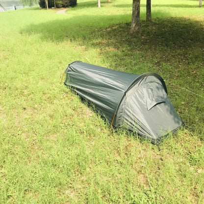 Lightweight bivy tent next to a backpack, illustrating its portability for hiking.