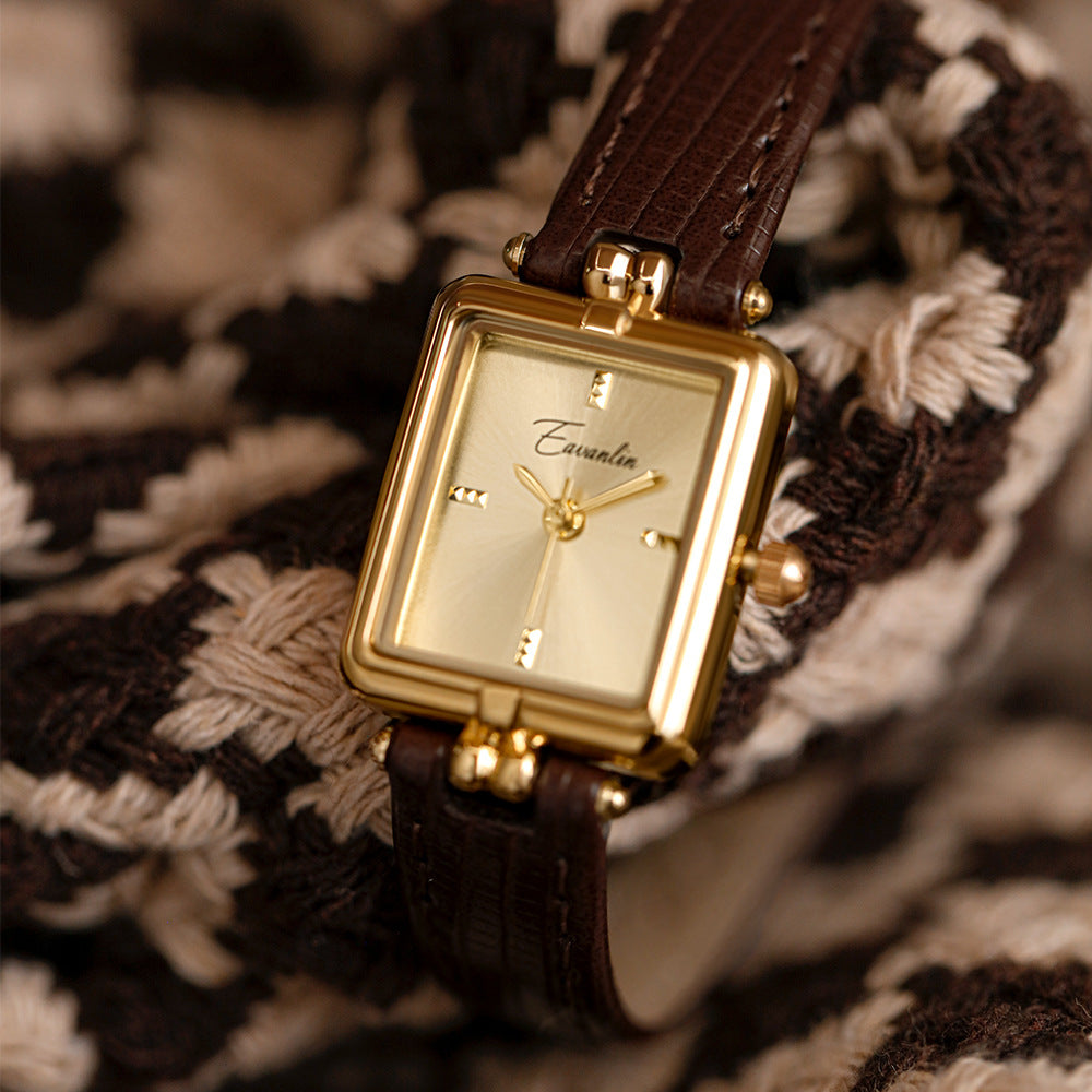 Slim profile of a stylish unisex watch with a black faux leather strap and a vibrant gold face. Modern accessory.