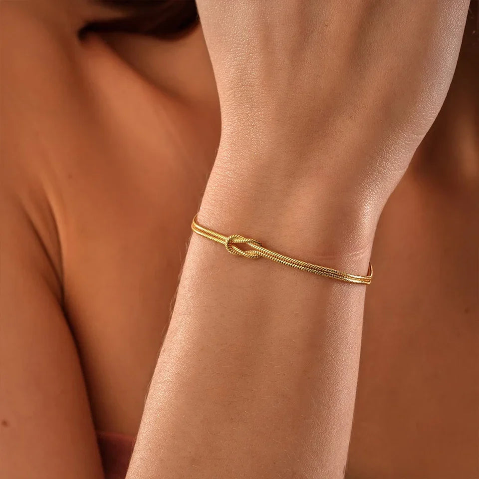 Close-up of a minimalist Endless Knot stainless steel chain bracelet, elegant unisex jewelry on a model's wrist.