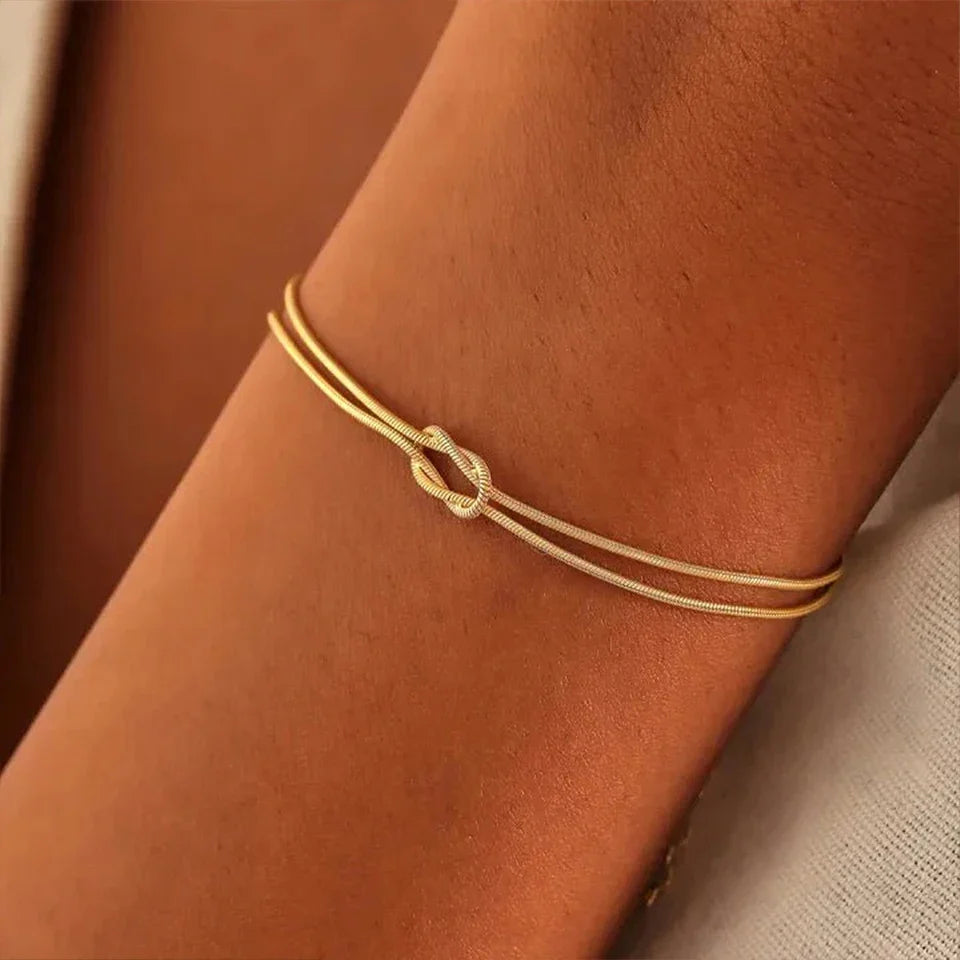 Modern unisex Endless Knot chain bracelet in polished stainless steel, symbolic minimalist design, adjustable fit.