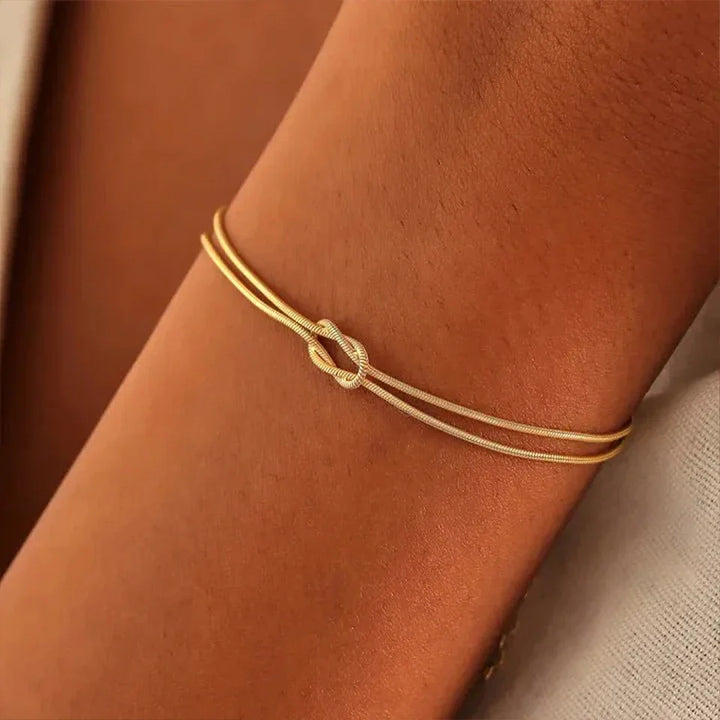 Modern unisex Endless Knot chain bracelet in polished stainless steel, symbolic minimalist design, adjustable fit.